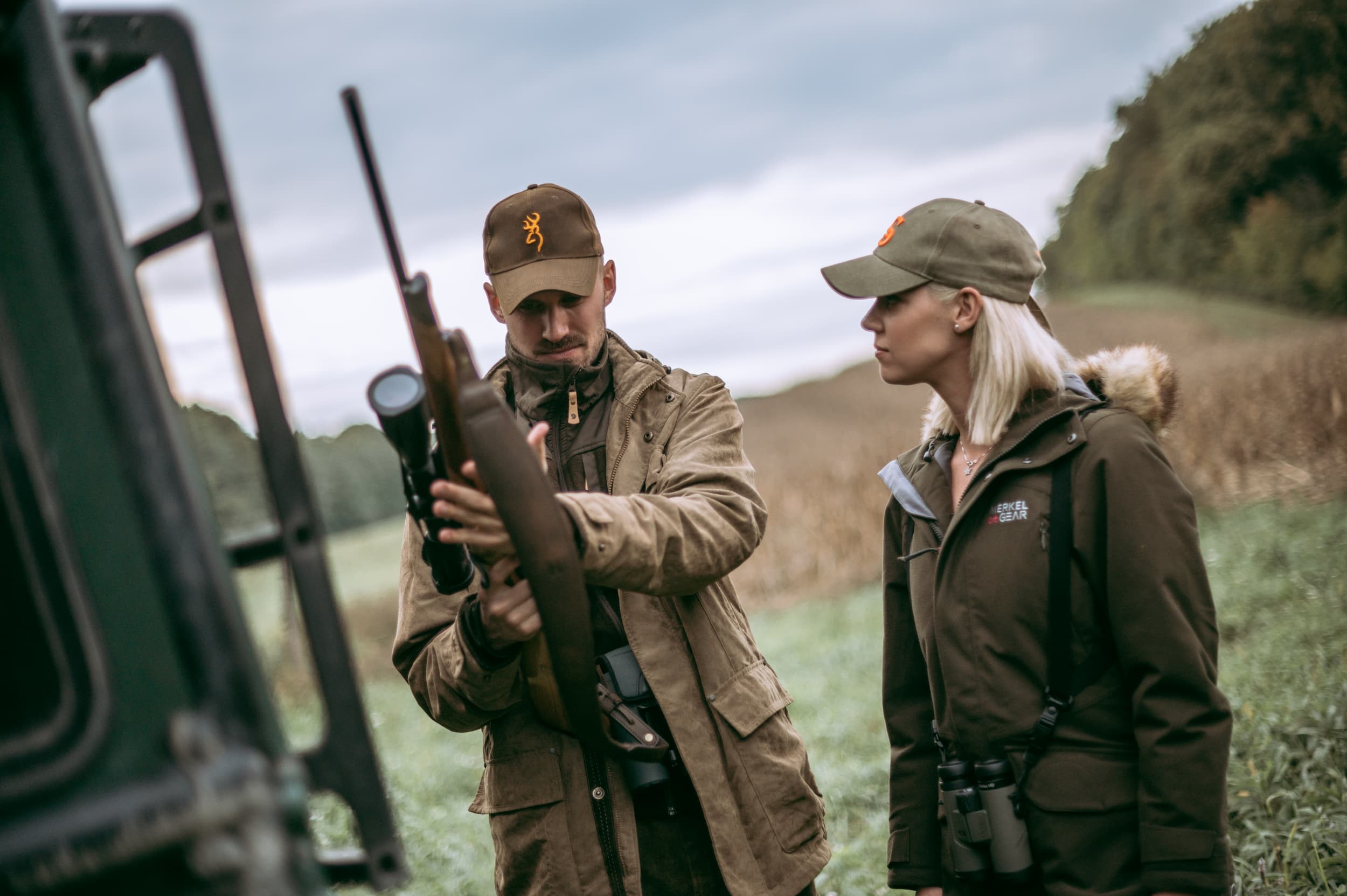 A man and woman observe a hunting gun, contemplating its design and functionality for their next hunting expedition.